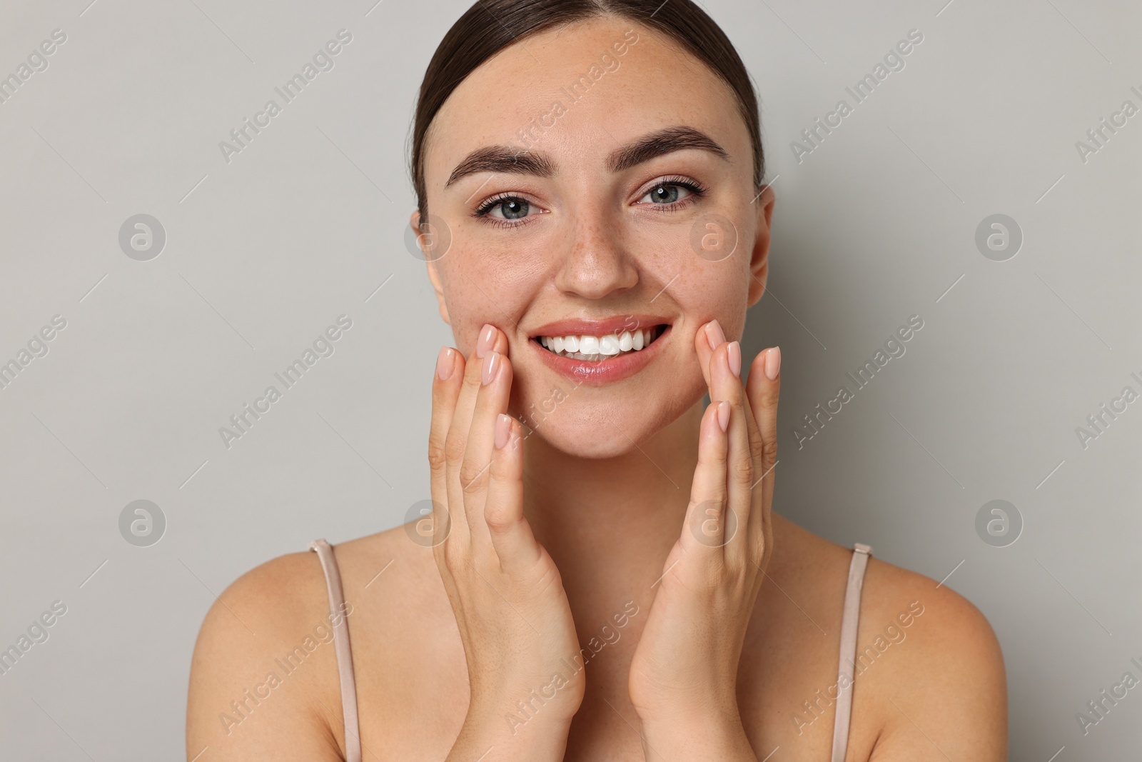 Photo of Face massage. Beautiful young woman with healthy skin on grey background