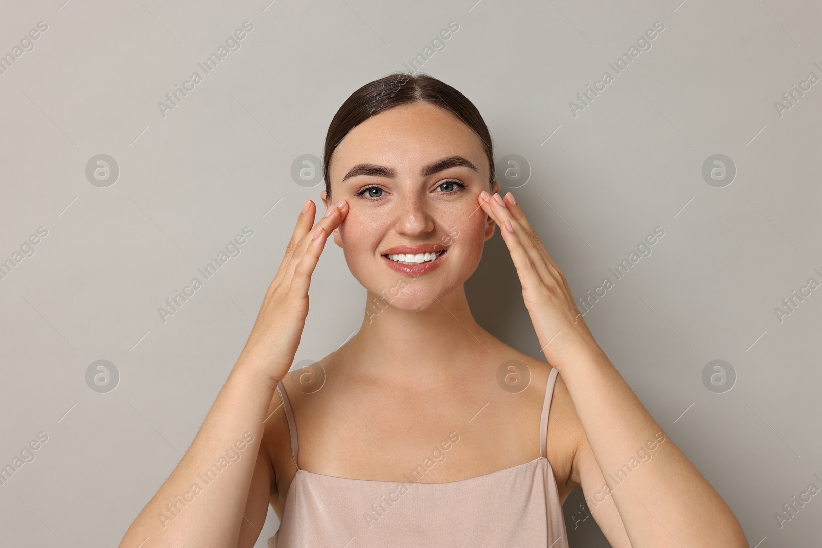 Photo of Face massage. Beautiful young woman with healthy skin on grey background