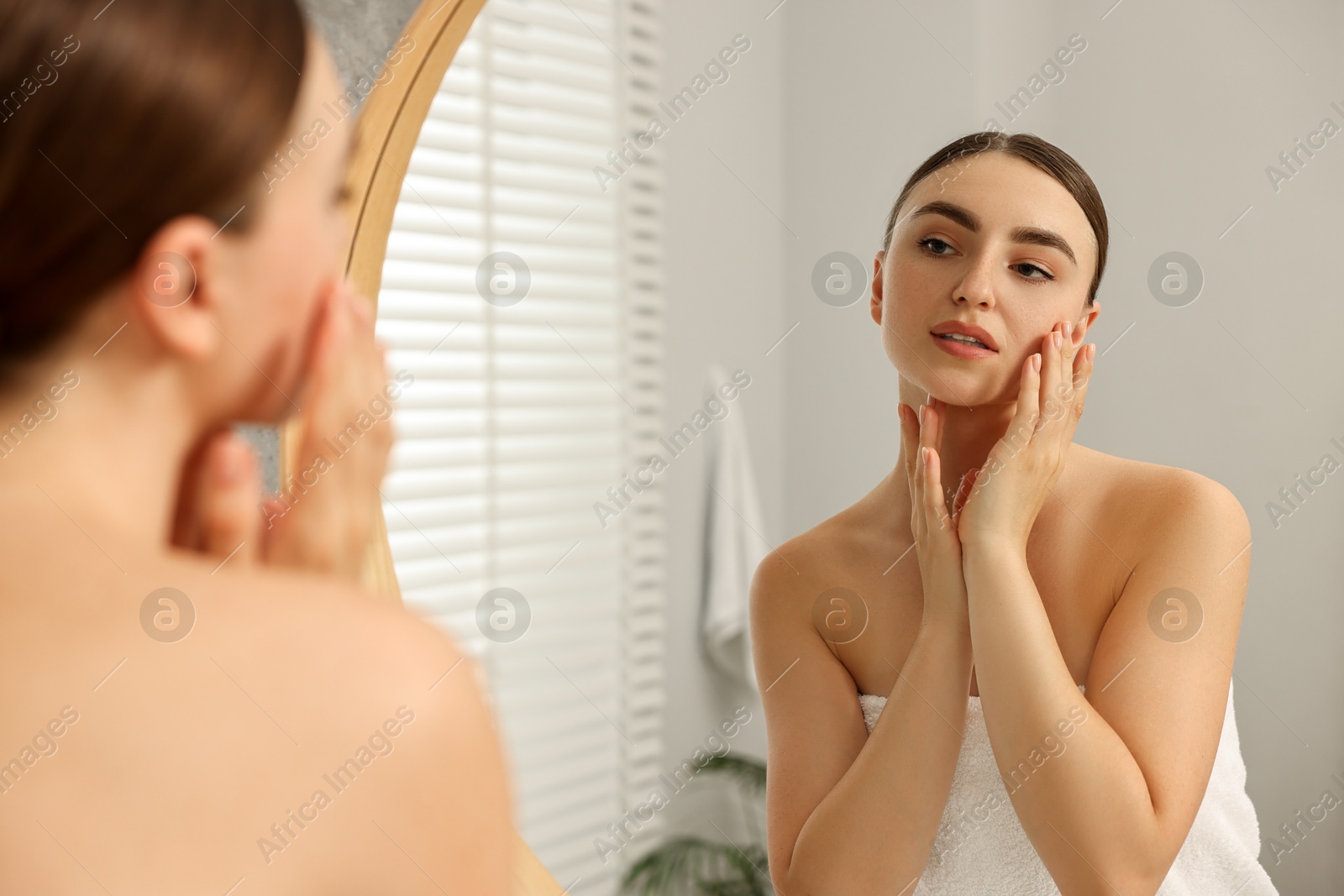 Photo of Face massage. Beautiful young woman with healthy skin near mirror at home