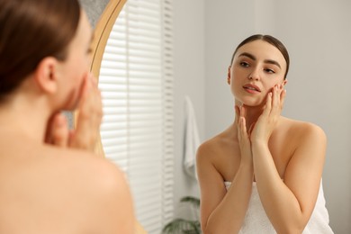 Face massage. Beautiful young woman with healthy skin near mirror at home