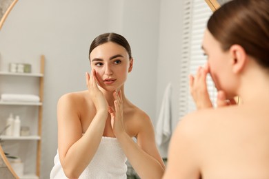 Photo of Face massage. Beautiful young woman with healthy skin near mirror at home