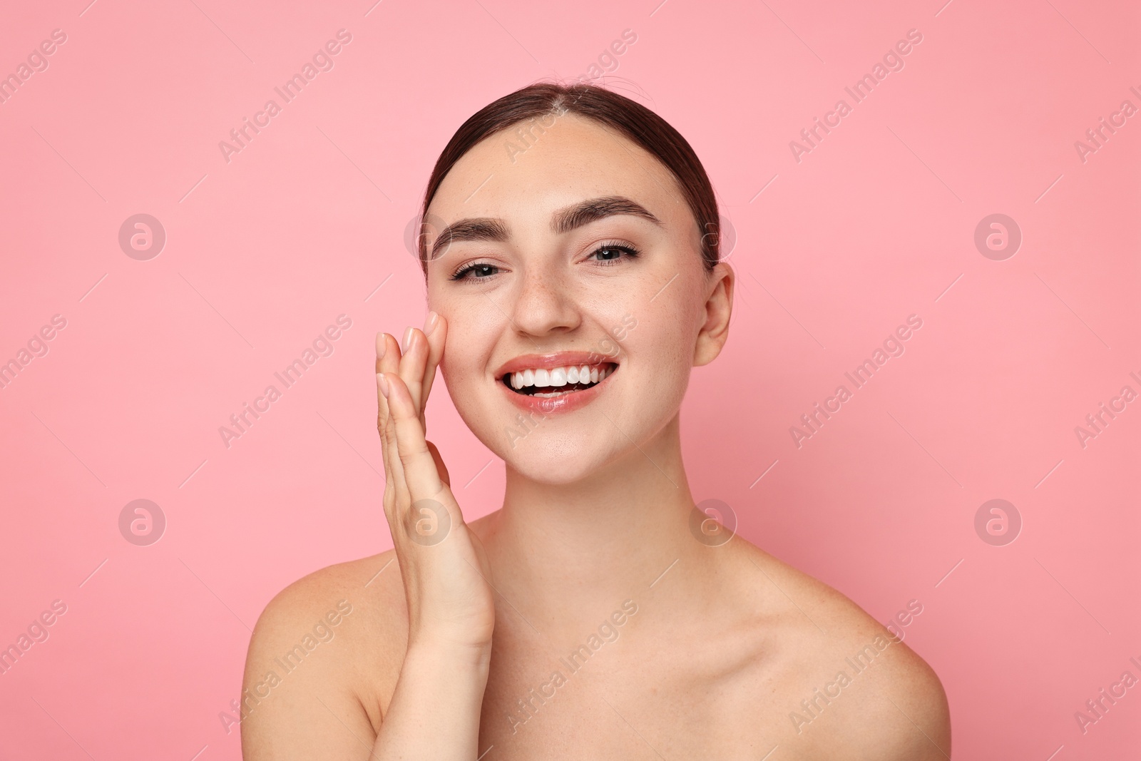 Photo of Face massage. Beautiful young woman with healthy skin on pink background