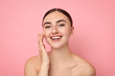 Face massage. Beautiful young woman with healthy skin on pink background