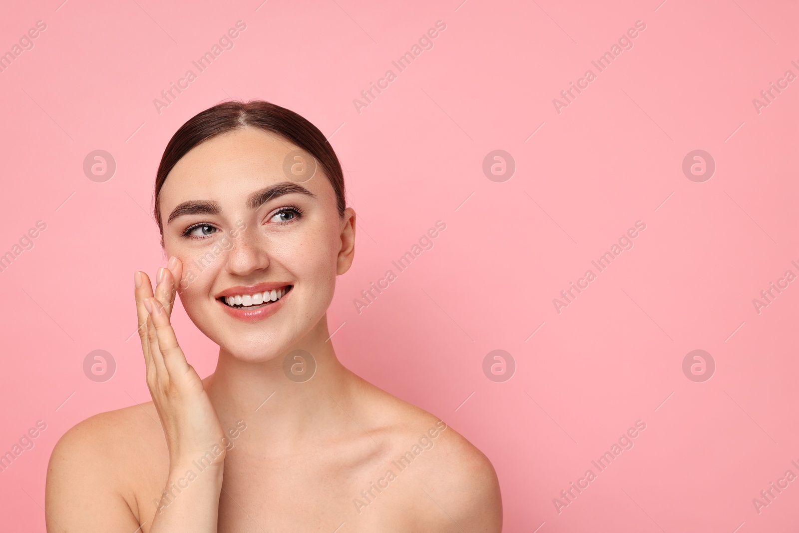 Photo of Face massage. Beautiful young woman with healthy skin on pink background, space for text