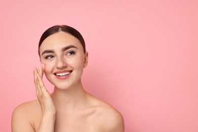 Face massage. Beautiful young woman with healthy skin on pink background, space for text