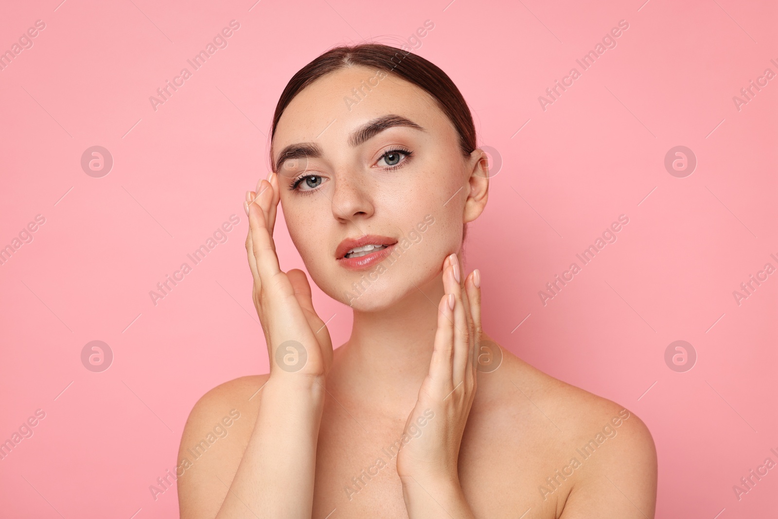 Photo of Face massage. Beautiful young woman with healthy skin on pink background