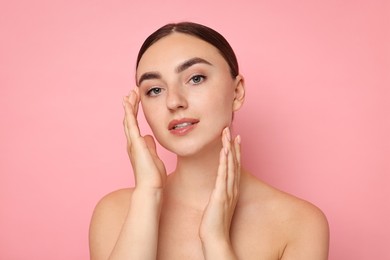 Photo of Face massage. Beautiful young woman with healthy skin on pink background