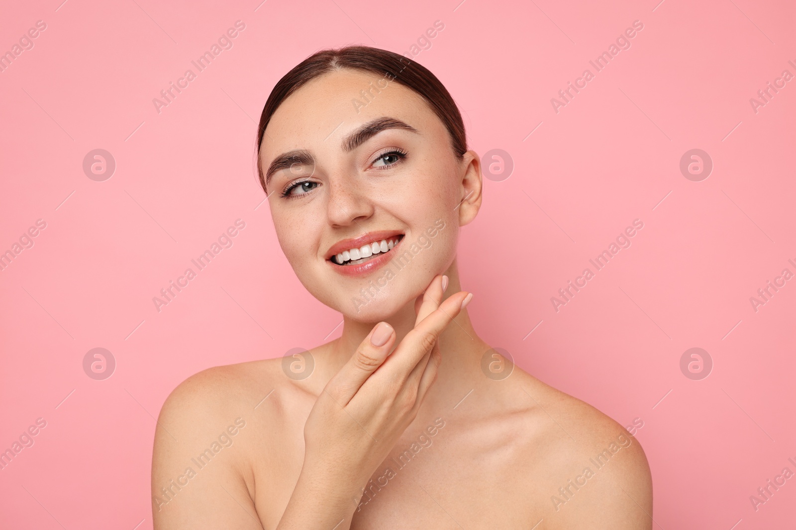 Photo of Face massage. Beautiful young woman with healthy skin on pink background