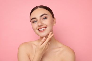 Face massage. Beautiful young woman with healthy skin on pink background