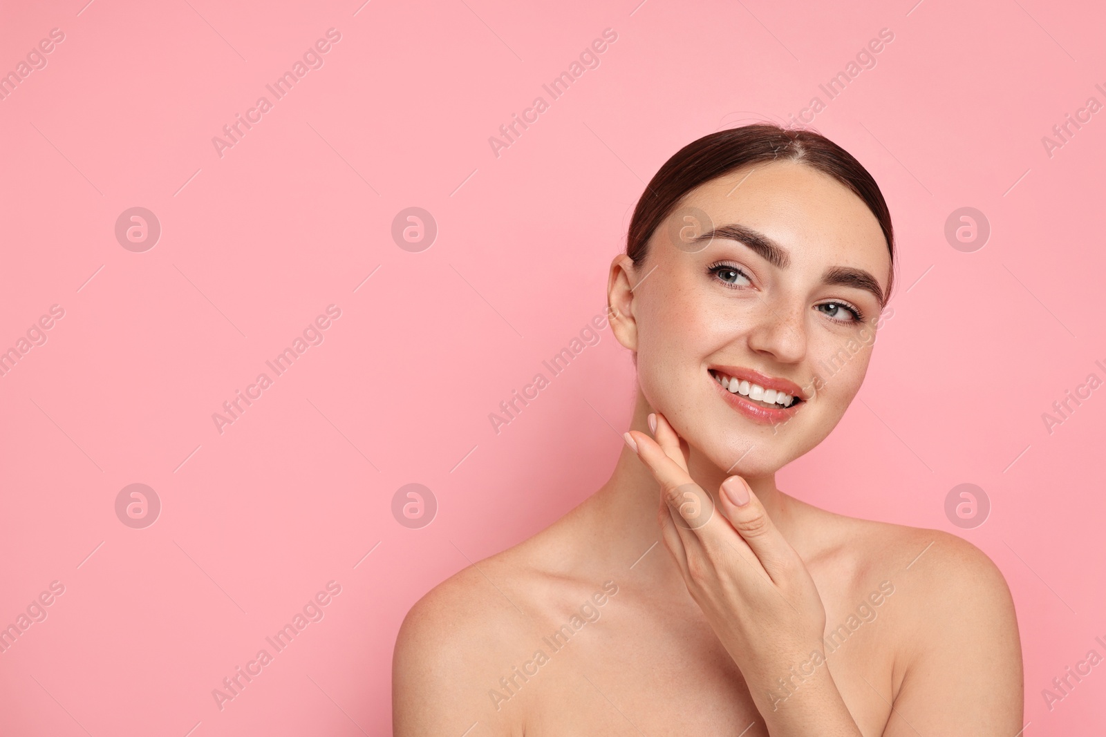 Photo of Face massage. Beautiful young woman with healthy skin on pink background, space for text