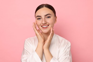 Photo of Face massage. Beautiful young woman with healthy skin on pink background