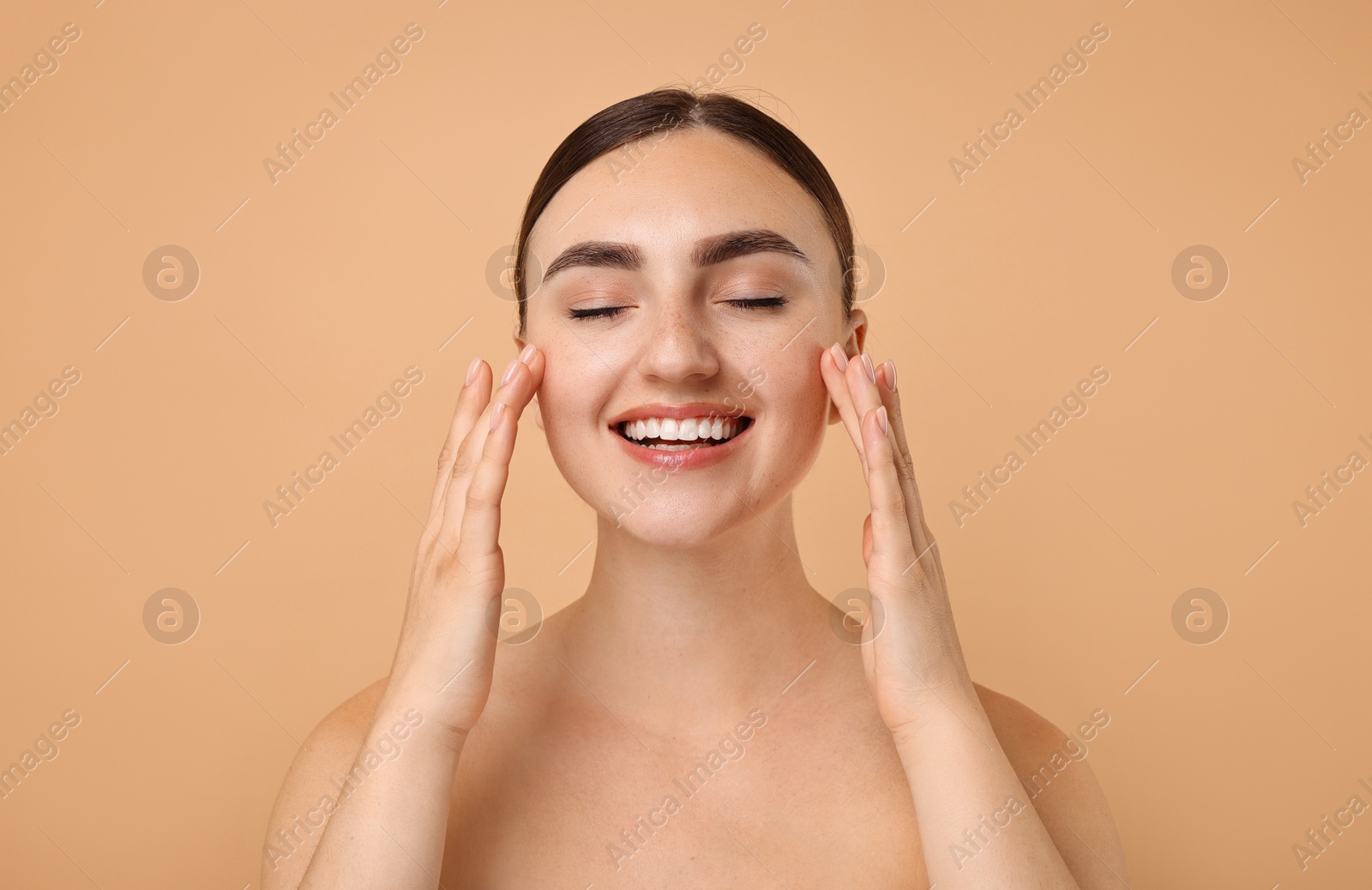 Photo of Face massage. Beautiful young woman with healthy skin on beige background