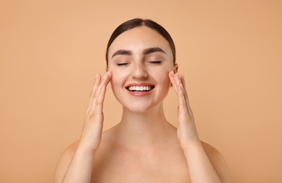 Face massage. Beautiful young woman with healthy skin on beige background