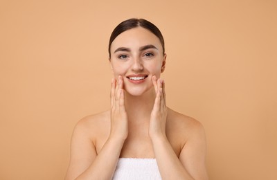 Beautiful young woman doing facial massage on beige background