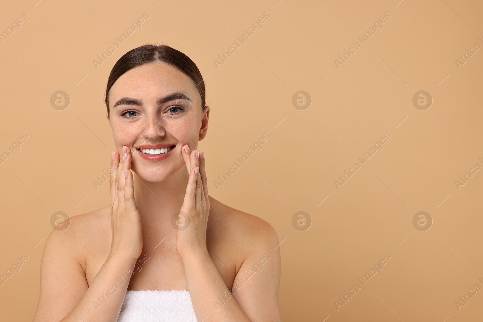 Photo of Face massage. Beautiful young woman with healthy skin on beige background, space for text