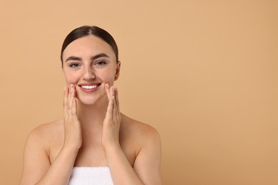 Face massage. Beautiful young woman with healthy skin on beige background, space for text