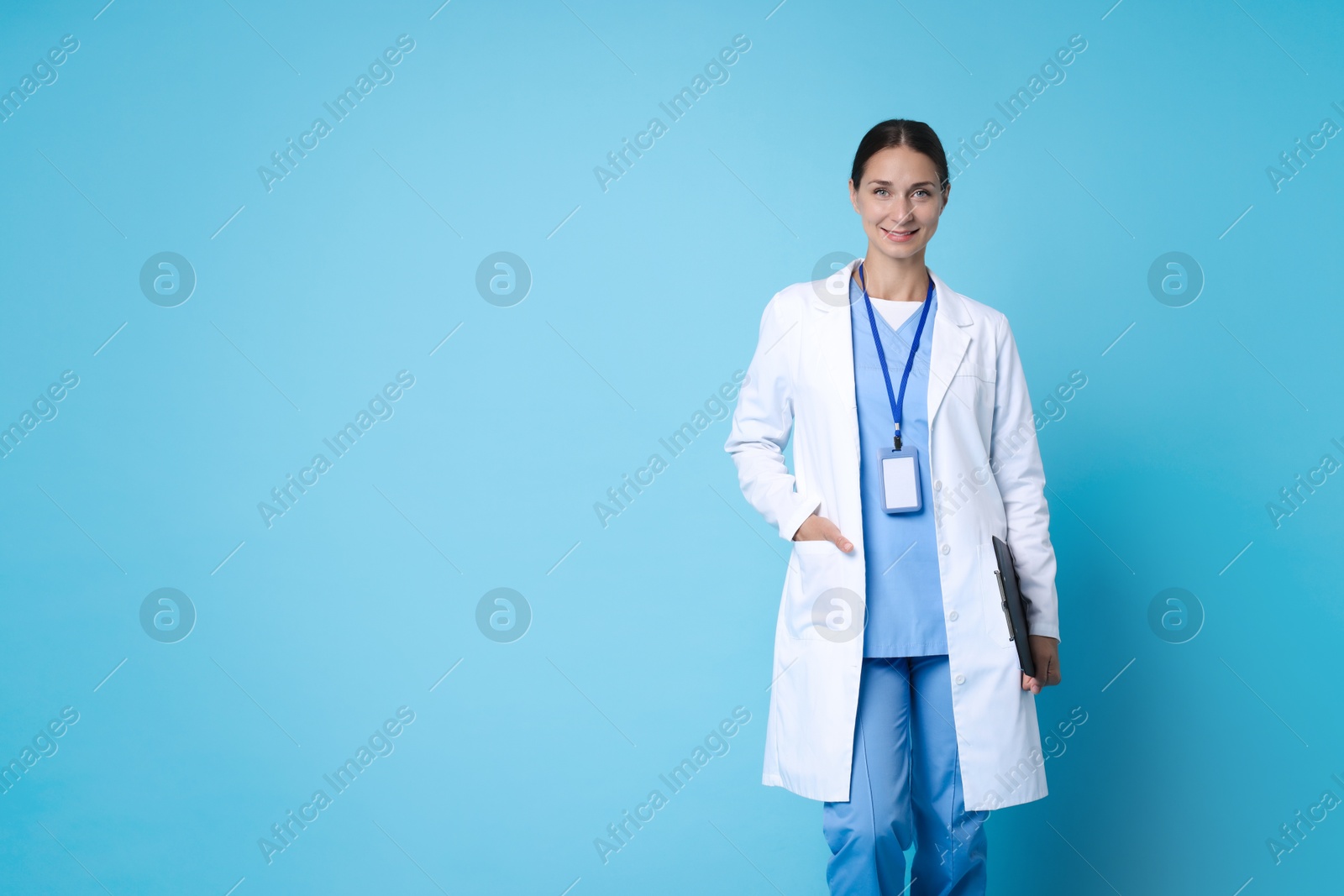 Photo of Nurse in medical uniform with clipboard on light blue background, space for text