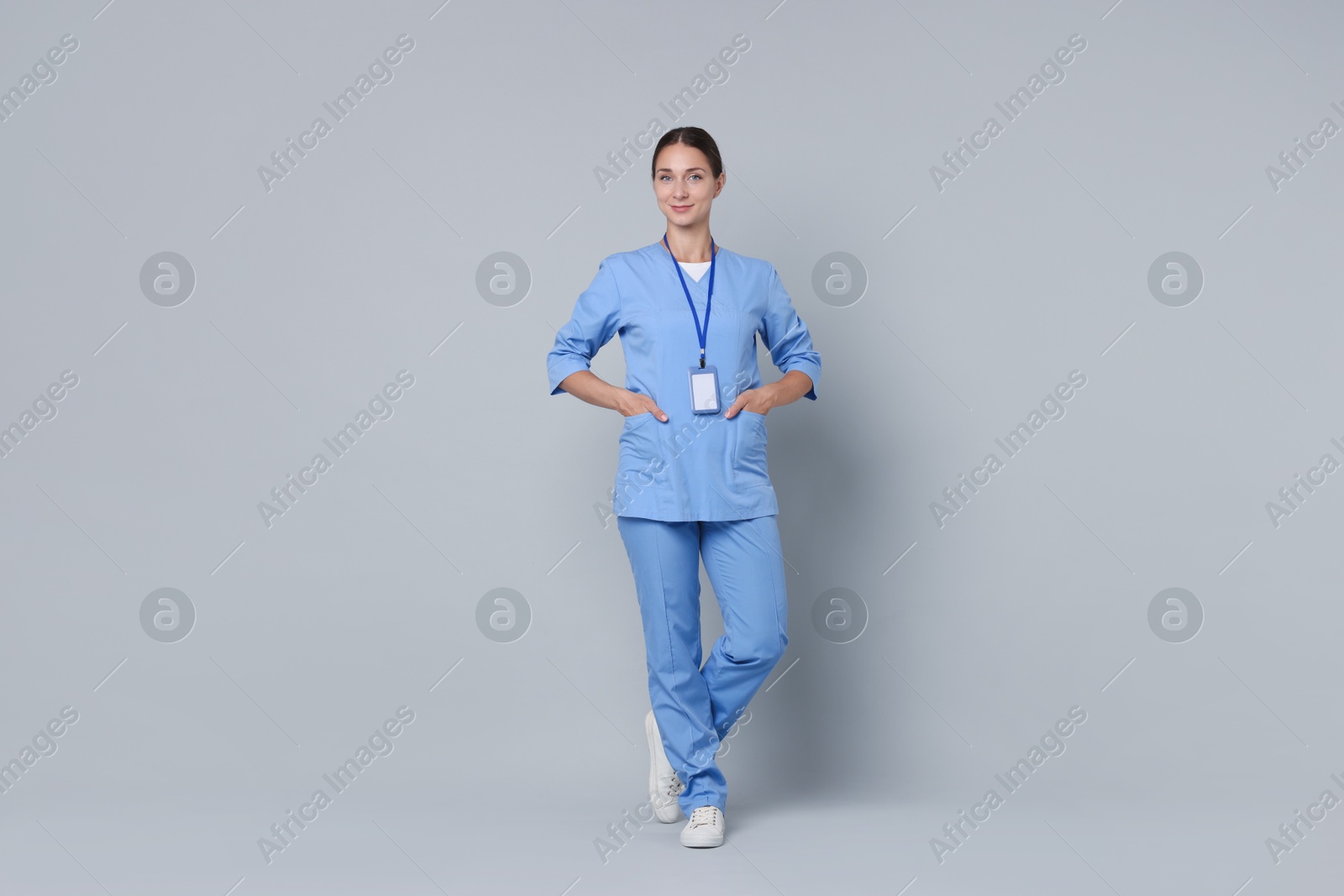 Photo of Nurse in medical uniform with badge on grey background