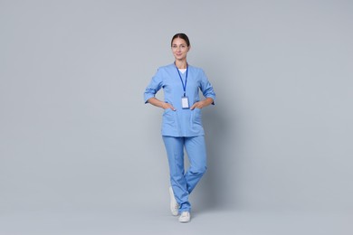 Nurse in medical uniform with badge on grey background