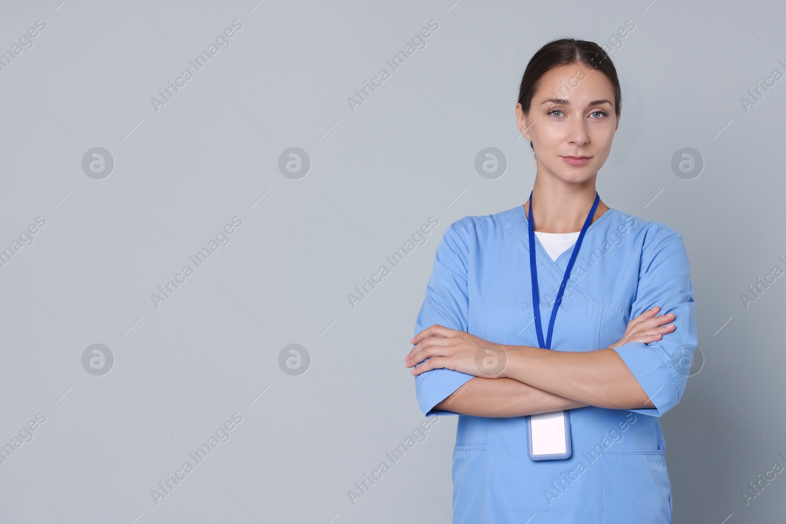 Photo of Nurse in medical uniform with badge on grey background, space for text