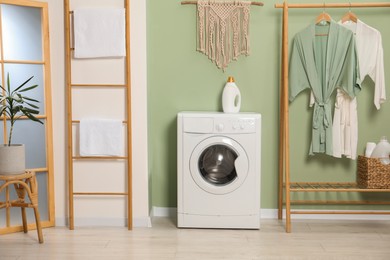 Photo of Washing machine, towels and detergent in laundry room