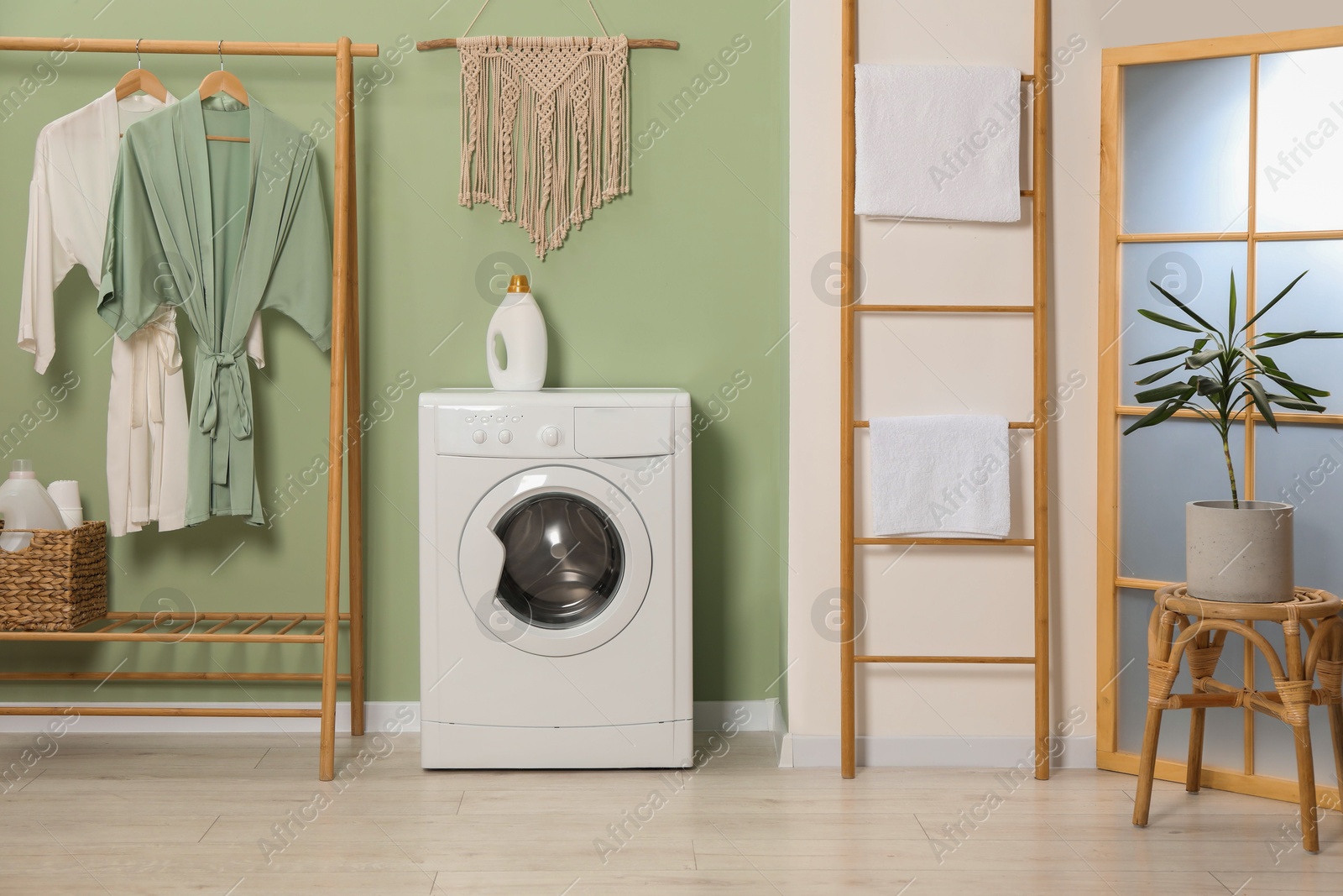 Photo of Washing machine, towels and detergent in laundry room