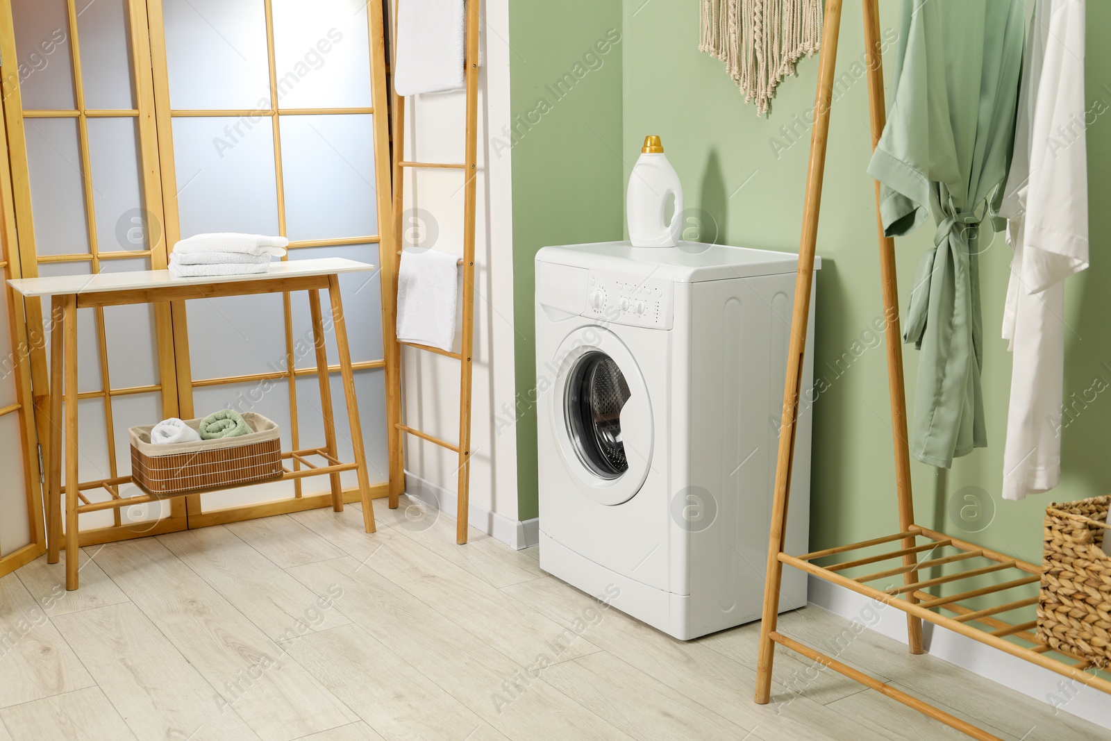 Photo of Washing machine, towels and detergent in laundry room