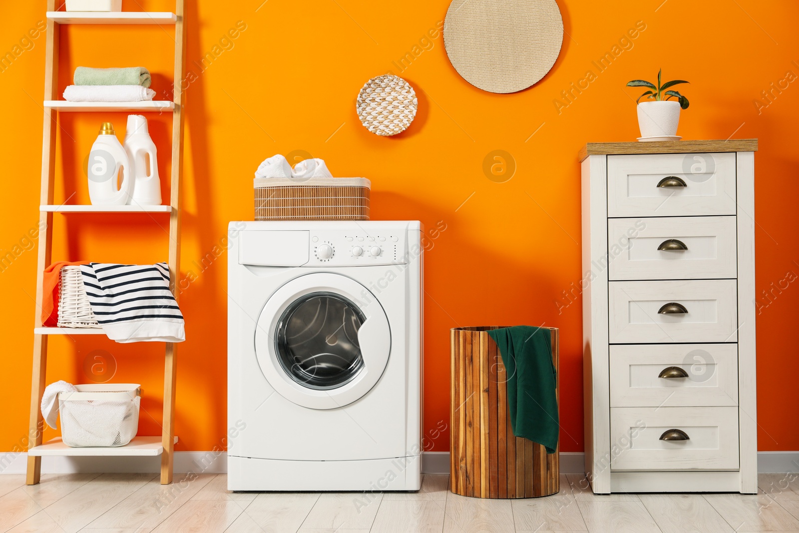 Photo of Washing machine, towels and detergents in laundry room