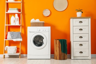 Photo of Washing machine, towels and detergents in laundry room