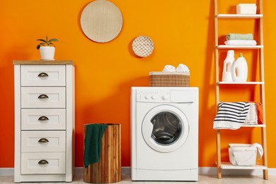 Photo of Washing machine, towels and detergents in laundry room