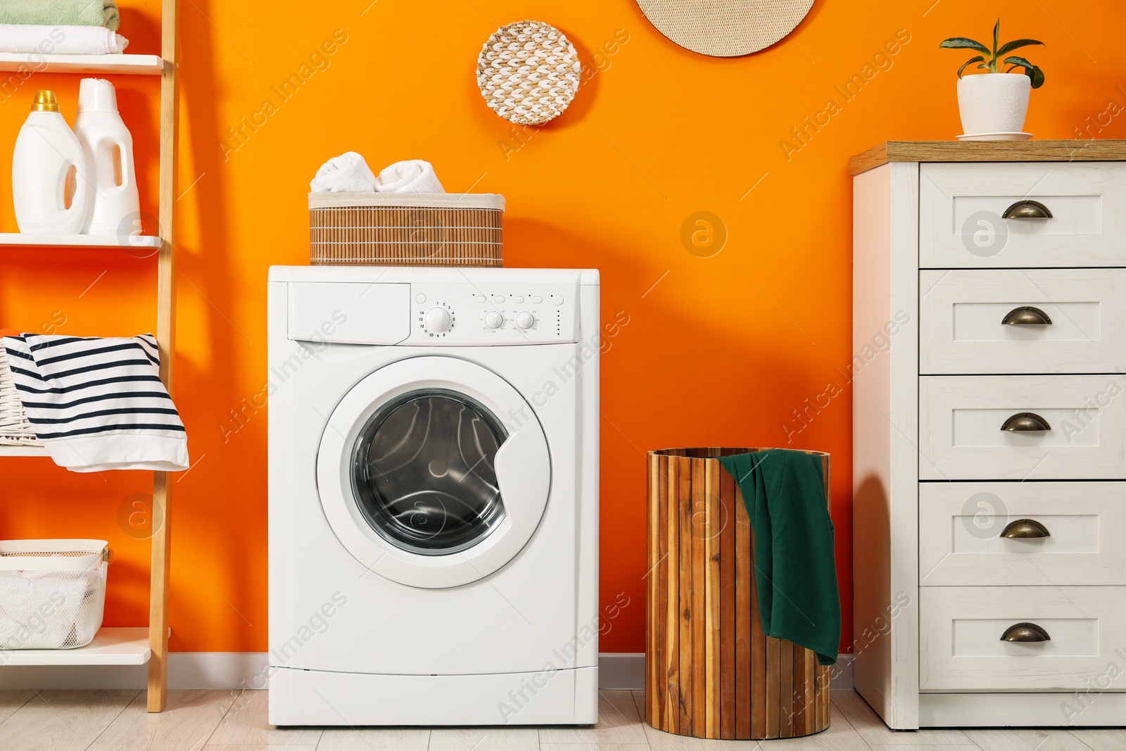 Photo of Washing machine, towels and detergents in laundry room