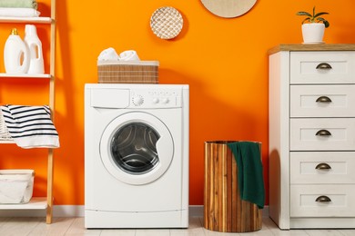 Photo of Washing machine, towels and detergents in laundry room