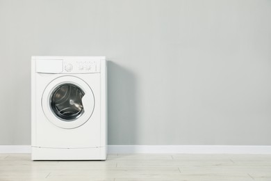 Photo of Washing machine near grey wall, space for text