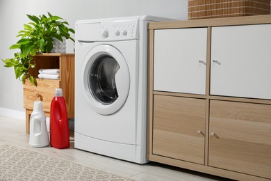 Photo of Washing machine, towels and detergents in laundry room