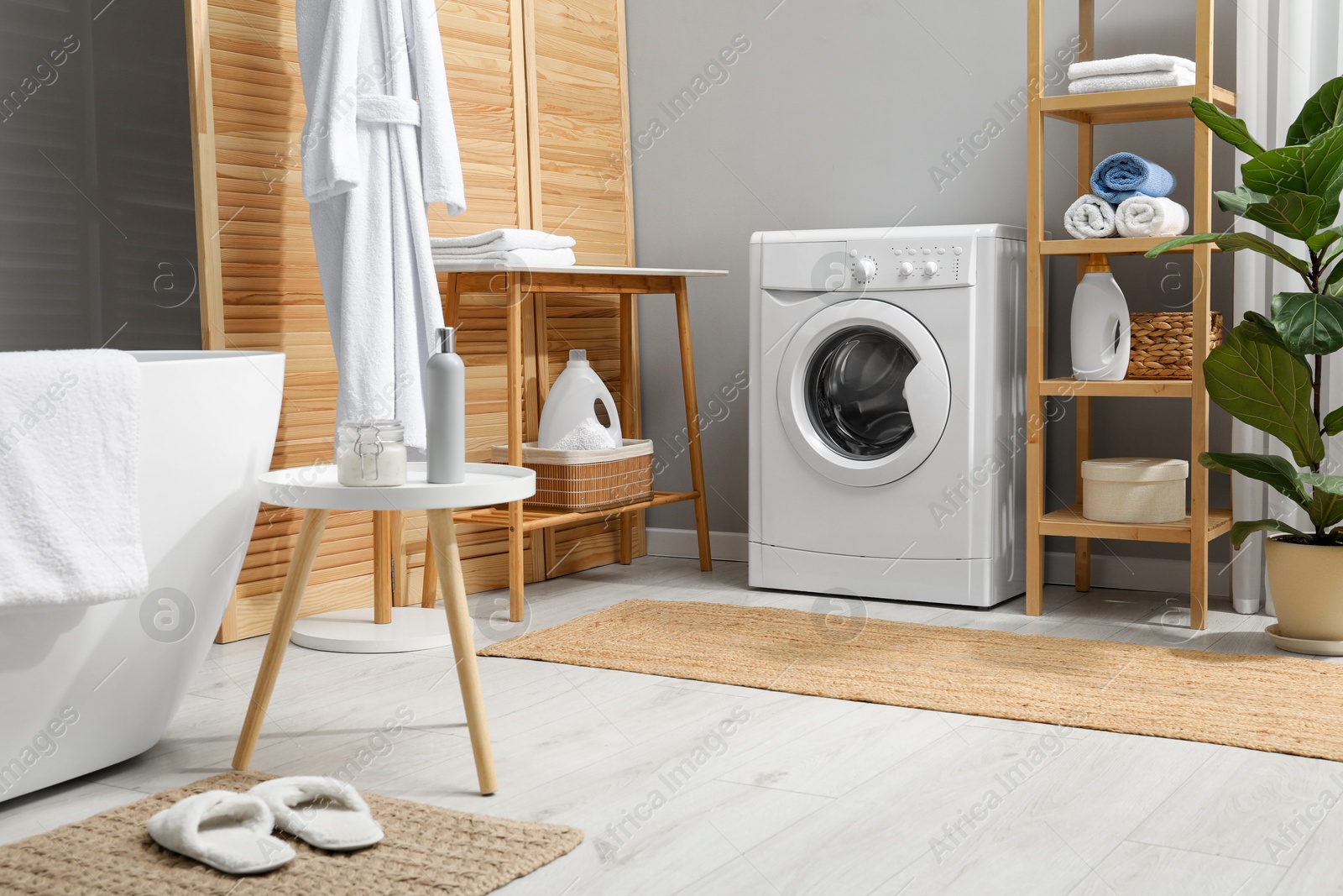 Photo of Washing machine, towels and detergents in bathroom