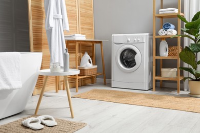 Photo of Washing machine, towels and detergents in bathroom