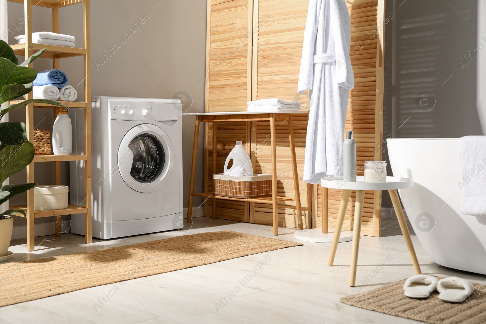 Photo of Washing machine, towels and detergents in bathroom