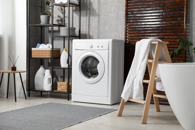 Photo of Washing machine, towels and detergents in bathroom