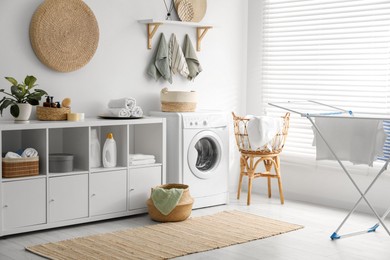 Photo of Washing machine, towels and detergents in laundry room