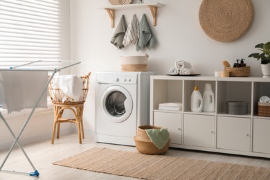 Photo of Washing machine, towels and detergents in laundry room