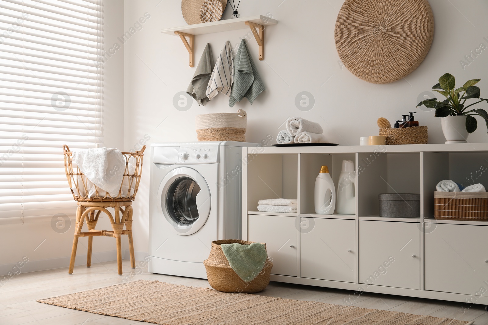 Photo of Washing machine, towels and detergents in laundry room