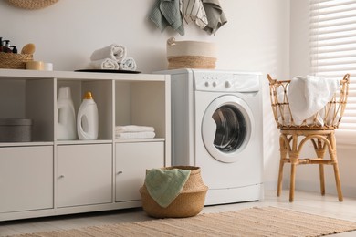 Photo of Washing machine, towels and detergents in laundry room