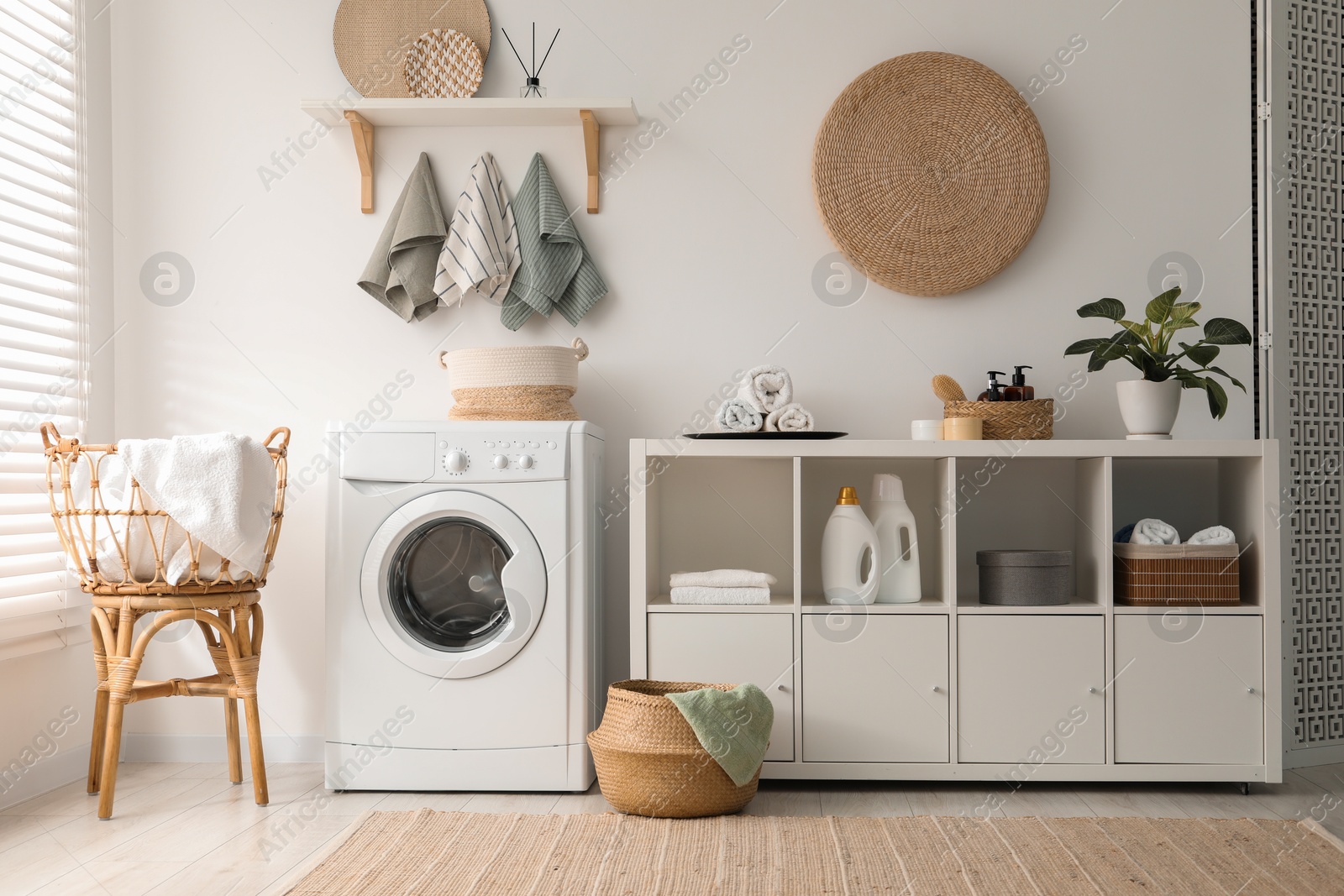 Photo of Washing machine, towels and detergents in laundry room