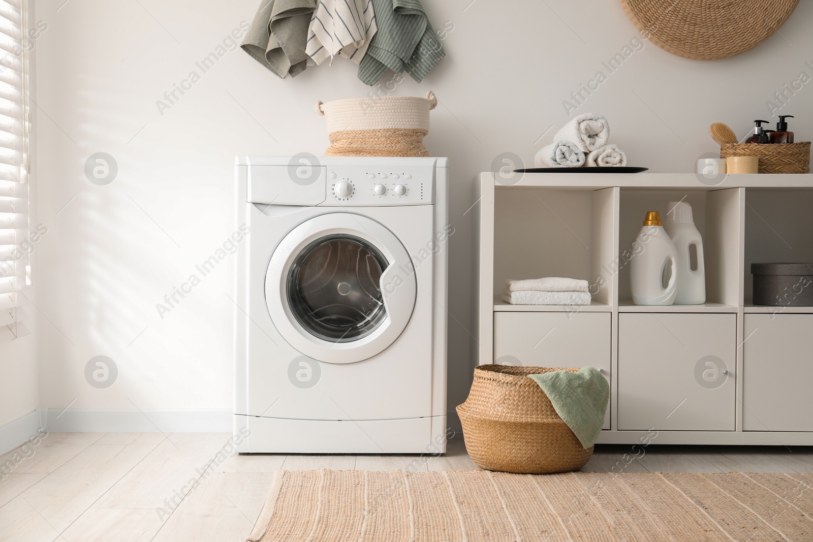 Photo of Washing machine, towels and detergents in laundry room