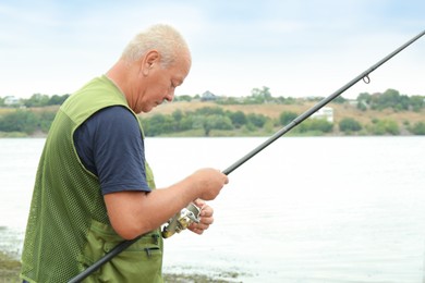 Fisherman with rod fishing near lake at summer