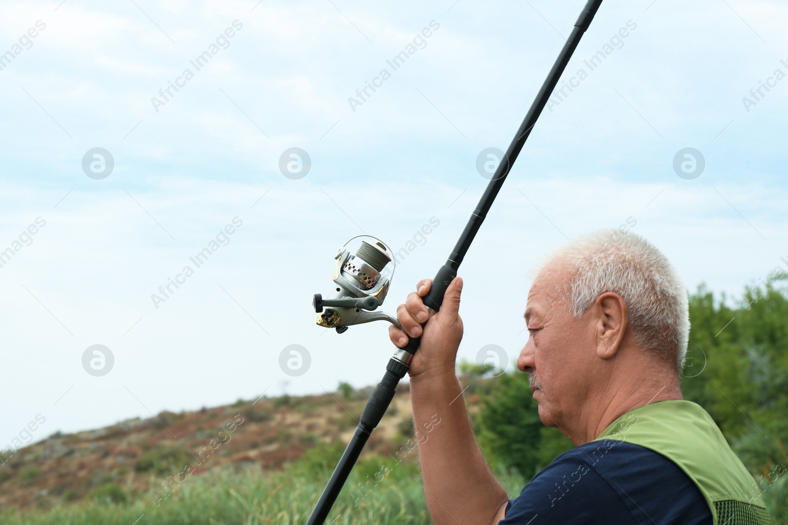 Photo of Fisherman with rod fishing near lake at summer