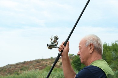 Fisherman with rod fishing near lake at summer