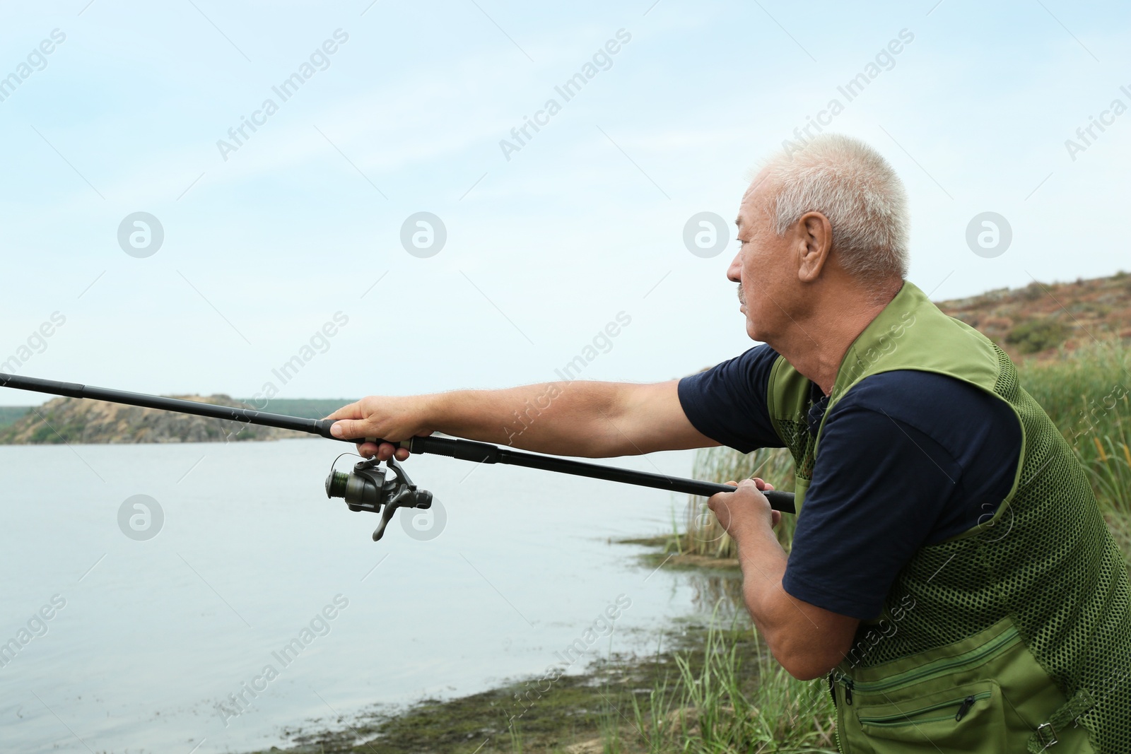 Photo of Fisherman with rod fishing near lake at summer