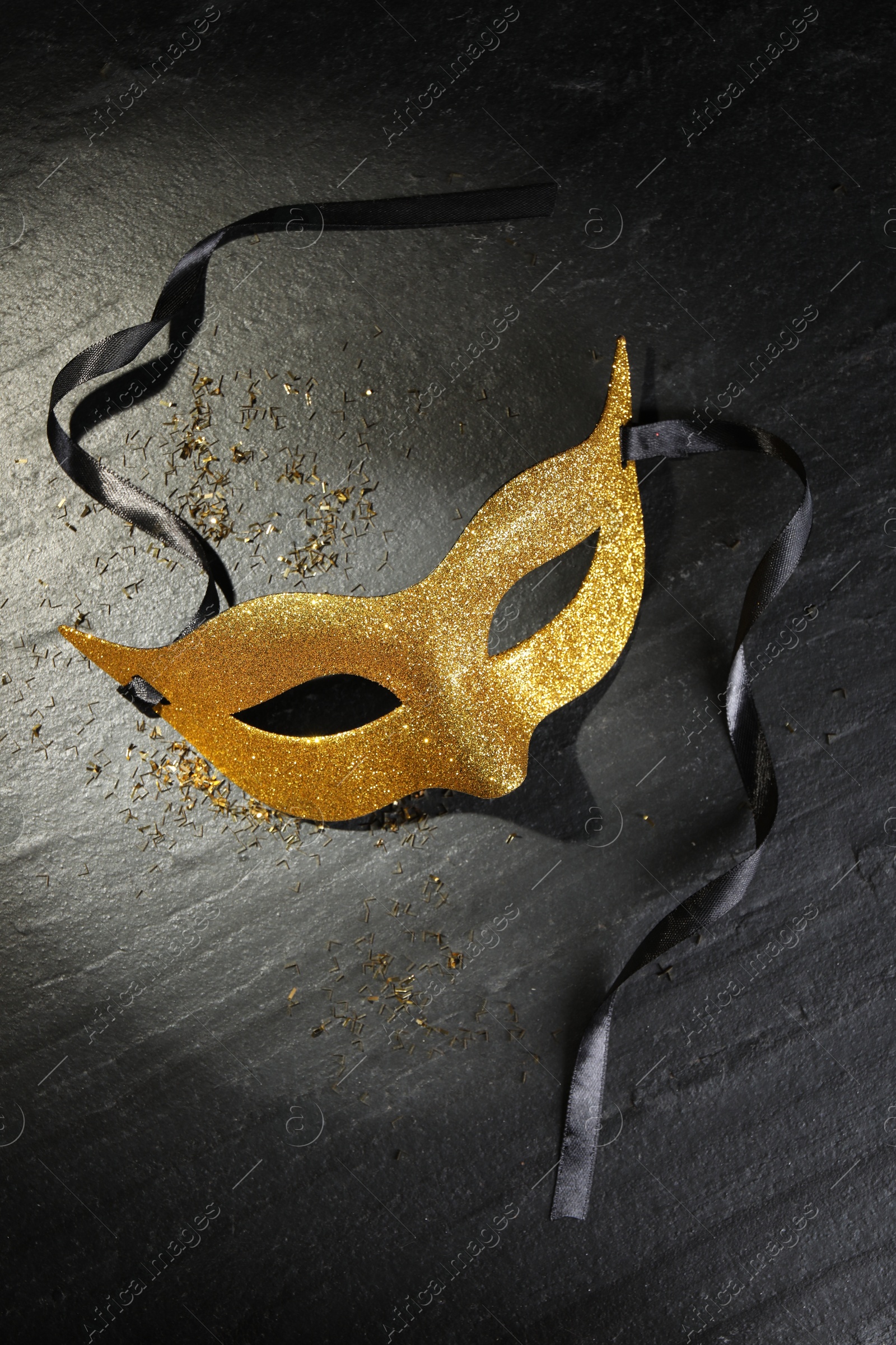 Photo of Beautiful golden carnival mask on grey textured table, top view