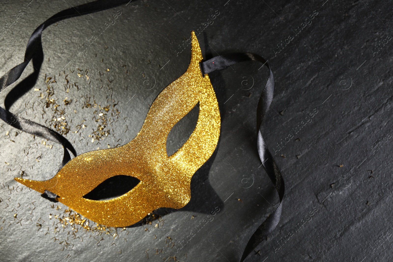 Photo of Beautiful golden carnival mask on grey textured table, top view